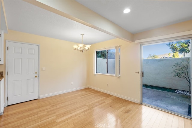 spare room featuring beam ceiling, light hardwood / wood-style floors, and a notable chandelier