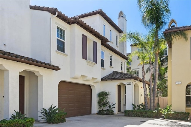 view of front facade with driveway, an attached garage, a tiled roof, and stucco siding