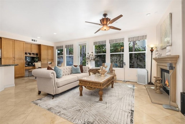 living area with light tile patterned floors, recessed lighting, visible vents, a ceiling fan, and a glass covered fireplace