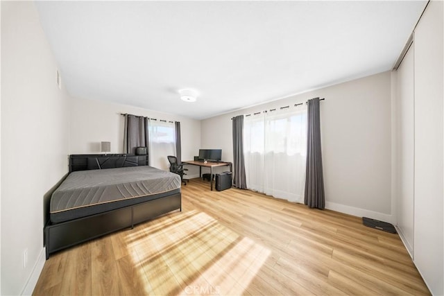 bedroom with multiple windows and light hardwood / wood-style floors