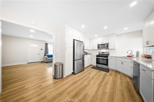 kitchen featuring appliances with stainless steel finishes, light hardwood / wood-style flooring, white cabinets, and sink