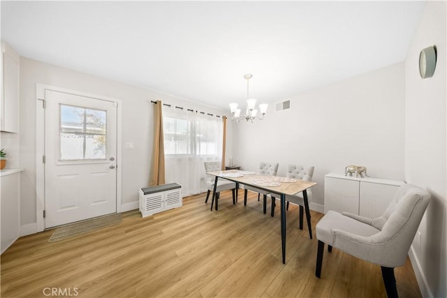 dining space featuring light wood-type flooring and a notable chandelier