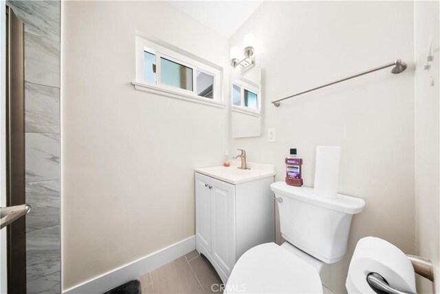 bathroom with toilet, vanity, and tile patterned flooring