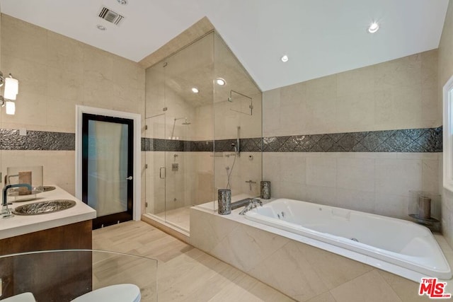 bathroom featuring vanity, tile walls, vaulted ceiling, and plus walk in shower