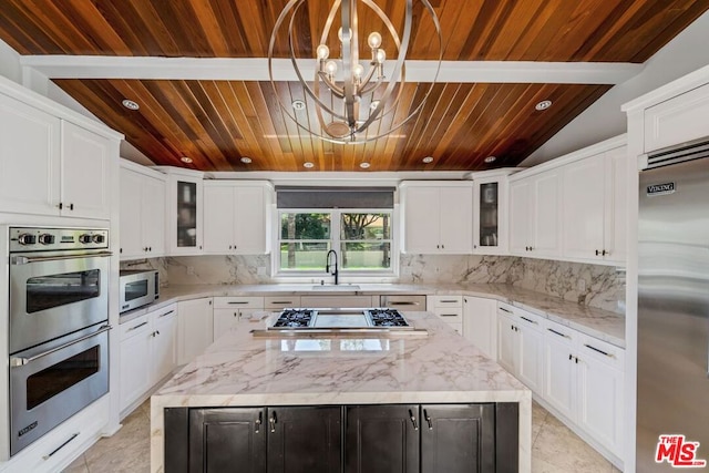 kitchen featuring backsplash, pendant lighting, a center island, white cabinetry, and appliances with stainless steel finishes