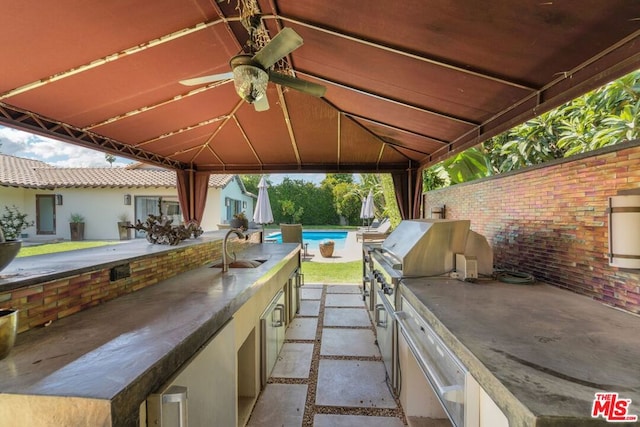 view of patio featuring ceiling fan, an outdoor kitchen, sink, and grilling area