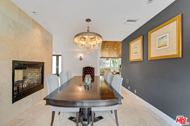 dining room featuring a tile fireplace and a notable chandelier