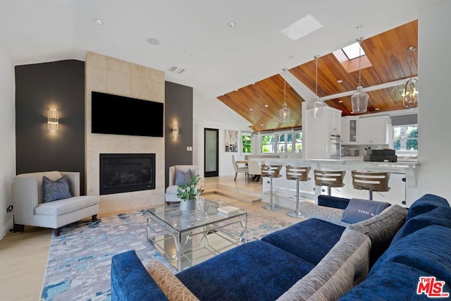 living room with high vaulted ceiling, wood ceiling, and a fireplace