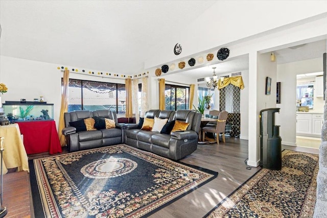 living room featuring dark wood-type flooring, vaulted ceiling, and an inviting chandelier