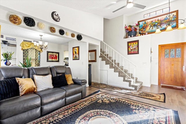 living room with wood-type flooring, ceiling fan with notable chandelier, and a textured ceiling