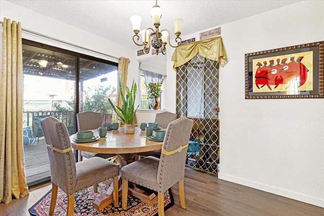 dining area with a textured ceiling, hardwood / wood-style floors, and an inviting chandelier