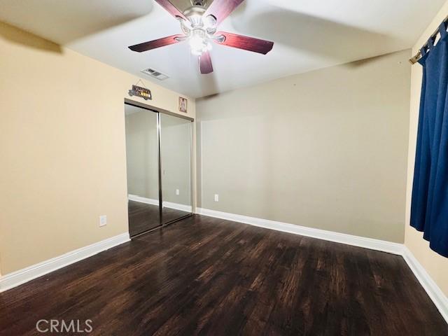 unfurnished bedroom featuring ceiling fan, hardwood / wood-style floors, and a closet