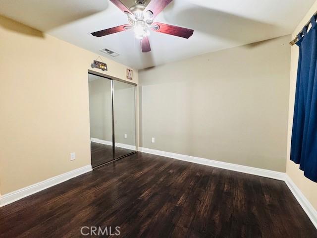 unfurnished bedroom with dark wood-type flooring, ceiling fan, and a closet