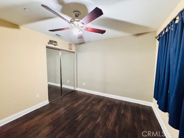 unfurnished bedroom featuring ceiling fan, a closet, and dark hardwood / wood-style flooring