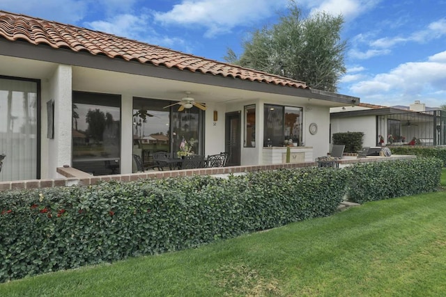 back of property with ceiling fan and a yard