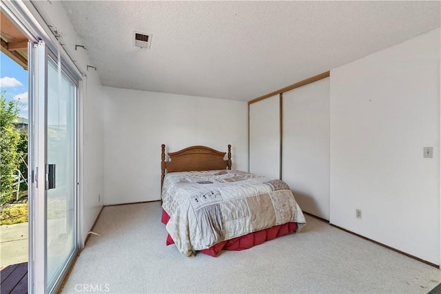 carpeted bedroom featuring access to outside, a closet, visible vents, and a textured ceiling