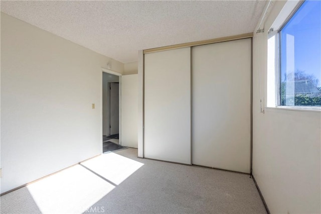 unfurnished bedroom featuring carpet, a closet, and a textured ceiling