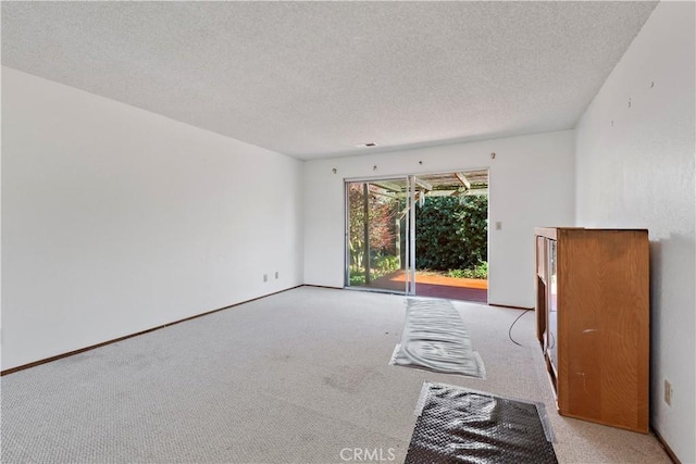 spare room featuring light colored carpet and a textured ceiling