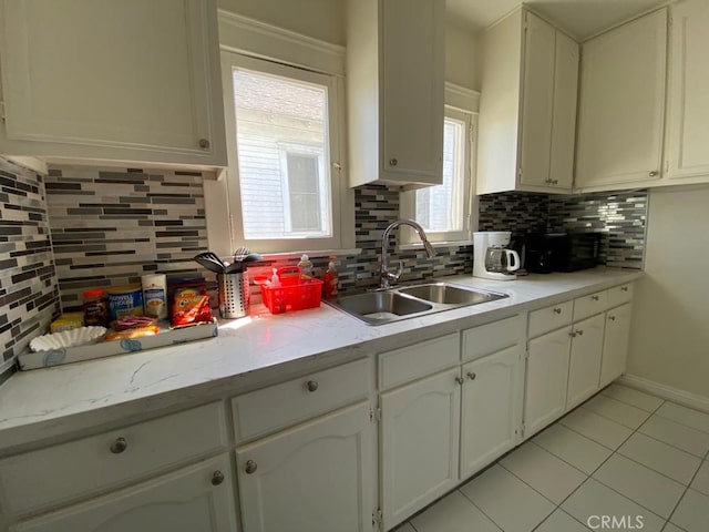 kitchen with white cabinets, backsplash, sink, and light tile patterned floors