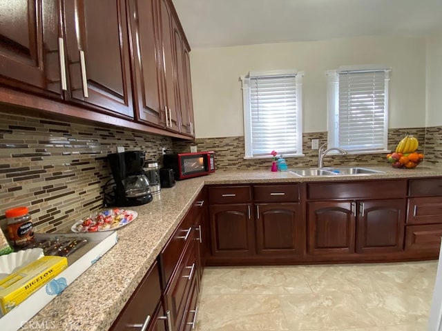 kitchen featuring tasteful backsplash, light tile patterned floors, light stone countertops, and sink