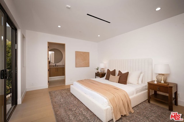 bedroom featuring light hardwood / wood-style floors, access to exterior, ensuite bathroom, and sink