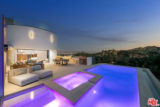 pool at dusk featuring an outdoor living space, an in ground hot tub, and a patio