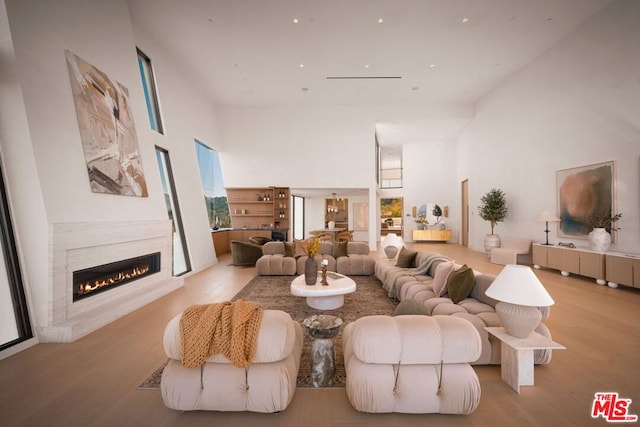 living room featuring light wood-type flooring and a towering ceiling