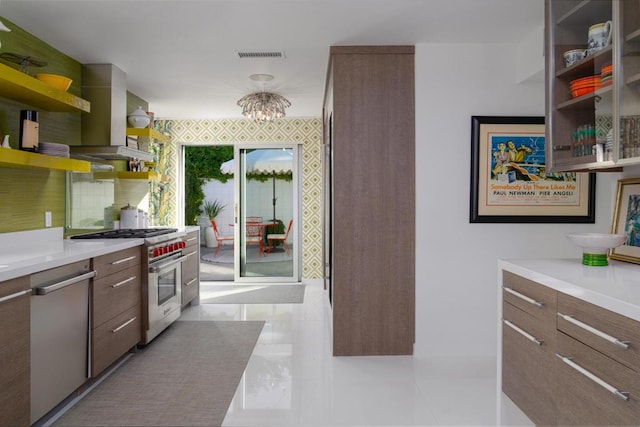 kitchen featuring island exhaust hood, backsplash, stainless steel appliances, and an inviting chandelier