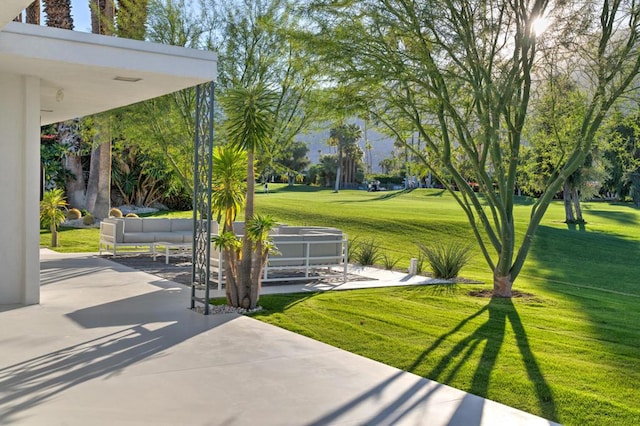 view of community featuring a lawn, an outdoor living space, and a patio