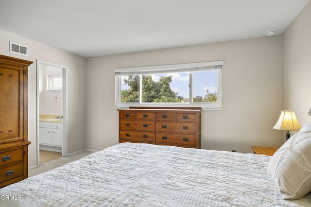 bedroom with ensuite bath, light carpet, and sink