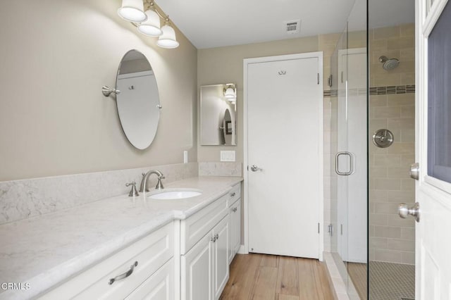 bathroom featuring a shower with shower door, vanity, and wood-type flooring