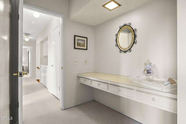 hall with a textured ceiling and light carpet