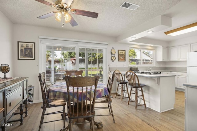 dining area featuring a textured ceiling, ceiling fan, and light wood-type flooring