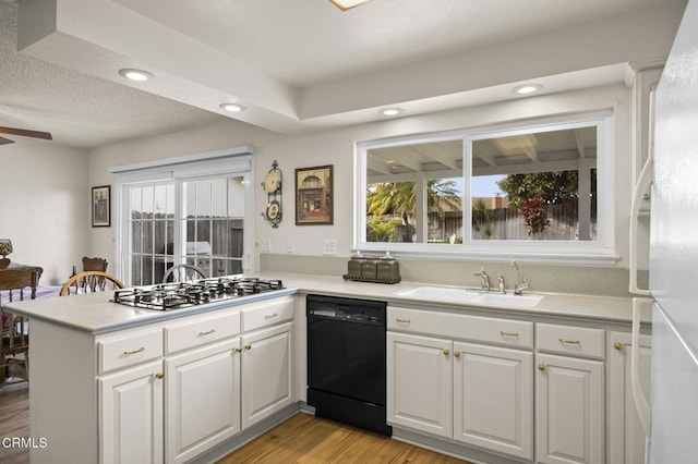 kitchen with white cabinets, black dishwasher, sink, kitchen peninsula, and light wood-type flooring