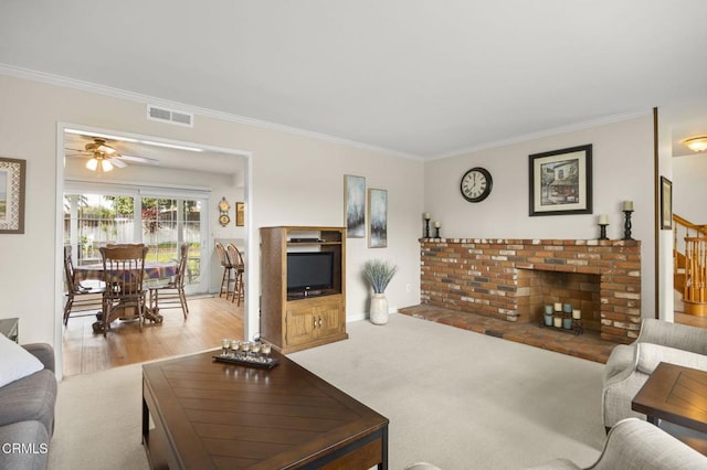 living room featuring ceiling fan, light colored carpet, a brick fireplace, and crown molding