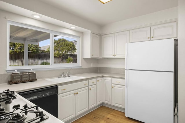 kitchen with white fridge, white cabinetry, light hardwood / wood-style floors, dishwasher, and sink