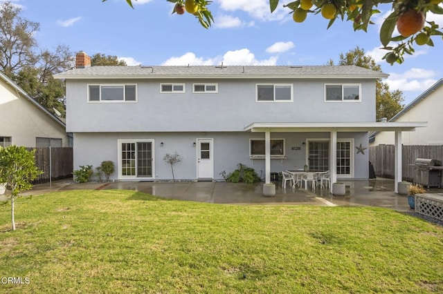 rear view of house with a lawn and a patio