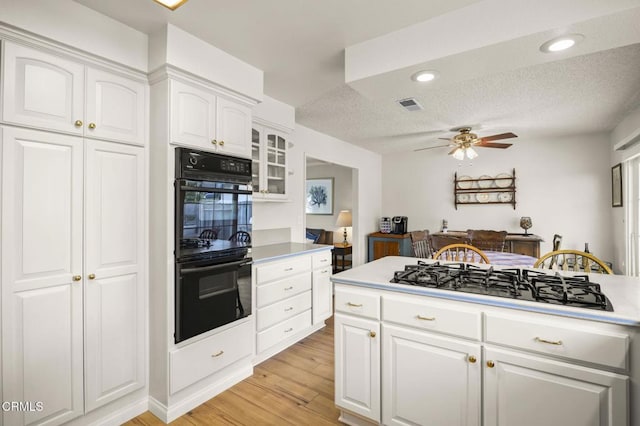 kitchen featuring a textured ceiling, white cabinetry, double oven, stainless steel gas cooktop, and ceiling fan