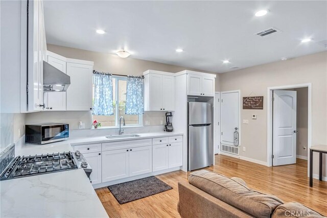 9022 Marlene Ave, Garden Grove, CA 92841 - kitchen with stainless steel appliances, under cabinet range hood, a sink, white cabinets, and light wood-type flooring