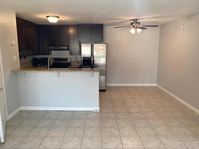 kitchen featuring kitchen peninsula, ceiling fan, stainless steel appliances, a breakfast bar, and sink