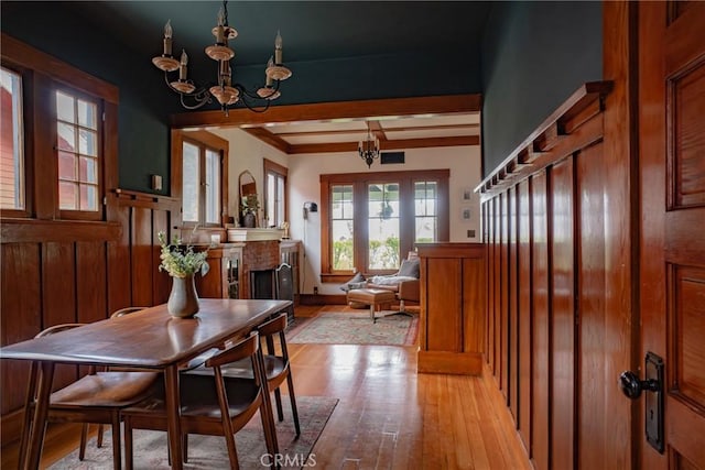 dining space featuring beamed ceiling, an inviting chandelier, and light hardwood / wood-style floors