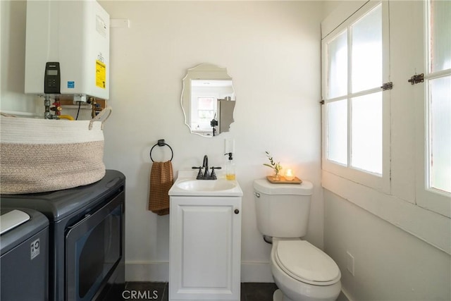 bathroom with a wealth of natural light, tankless water heater, washer and clothes dryer, and vanity