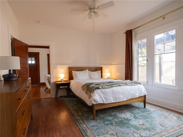 bedroom with ceiling fan, dark wood-type flooring, and multiple windows