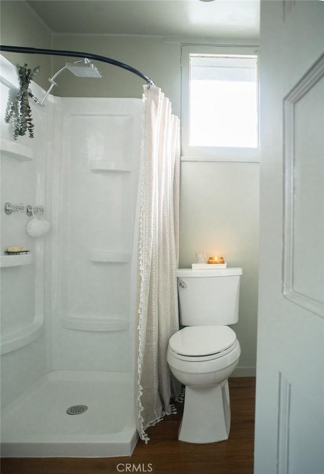 bathroom with walk in shower, toilet, and hardwood / wood-style floors