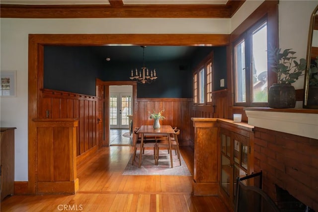 dining area with french doors, light hardwood / wood-style floors, plenty of natural light, and a notable chandelier