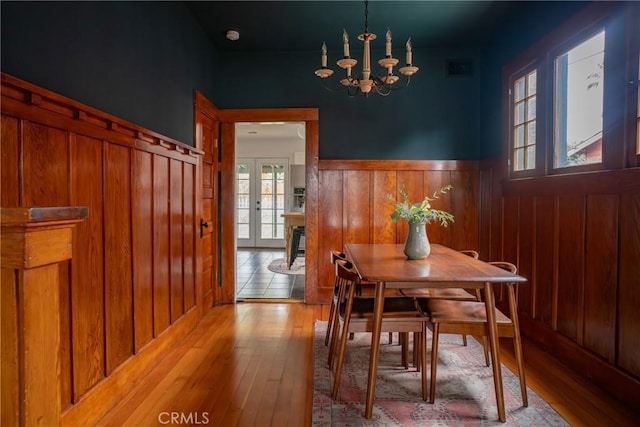 dining space with french doors, a chandelier, and light wood-type flooring