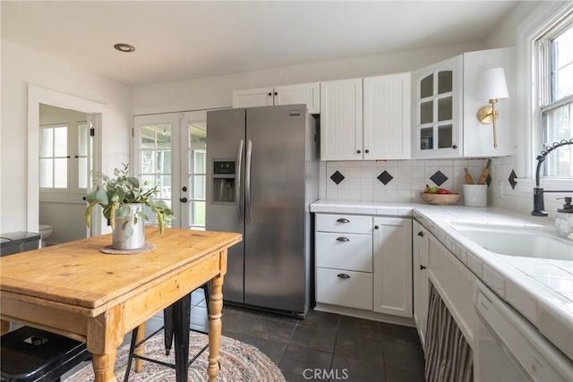 kitchen with dishwasher, white cabinetry, sink, stainless steel fridge with ice dispenser, and tile countertops