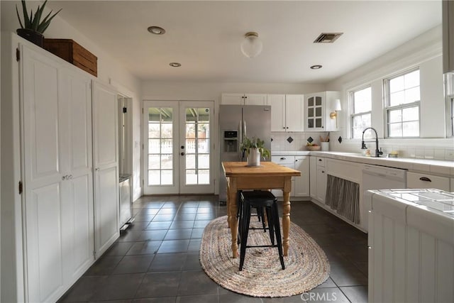 kitchen featuring white cabinetry, tile countertops, french doors, and tasteful backsplash