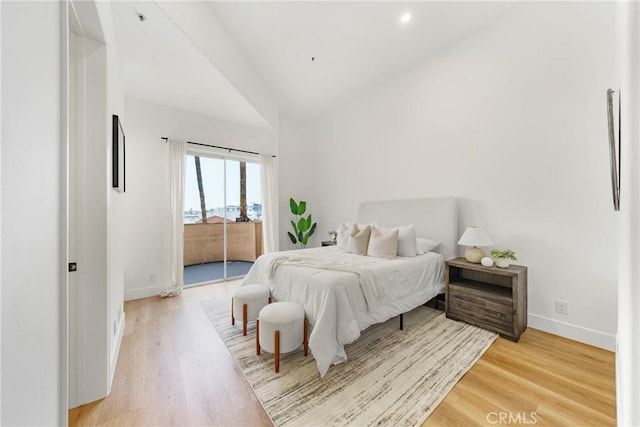 bedroom featuring lofted ceiling, access to exterior, and hardwood / wood-style floors