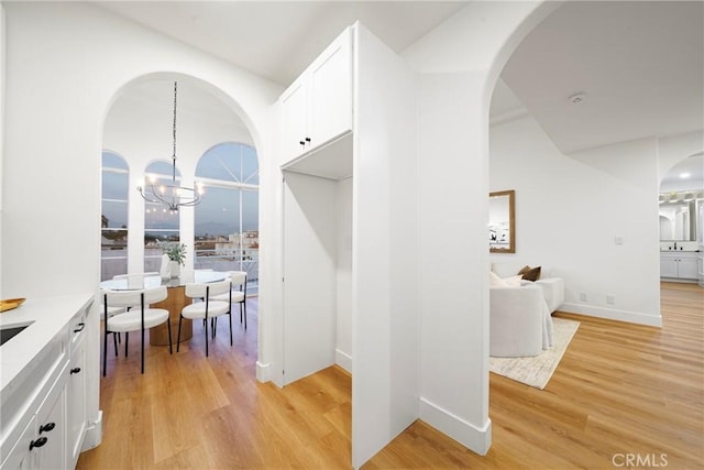 hall with light hardwood / wood-style floors and an inviting chandelier